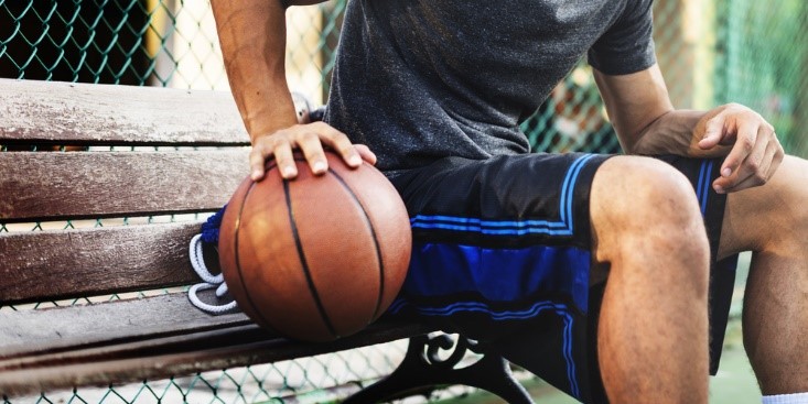 Basketball player on bench outdoors with ball