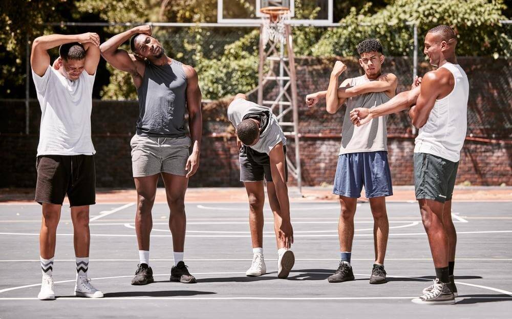 Five young basketball players warmup on an outdoor court
