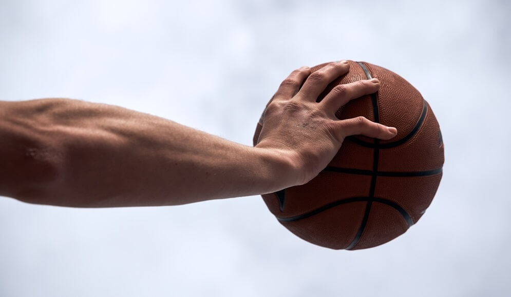 Man palming a basketball under a blue sky