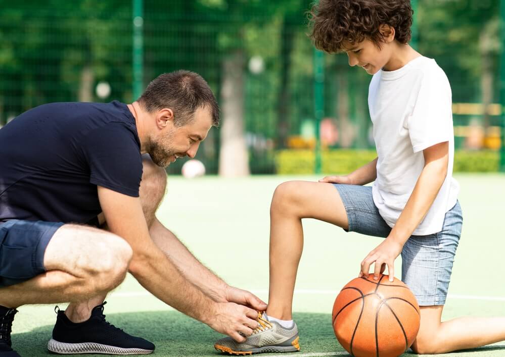 Man ties child's shoe on the basketball court