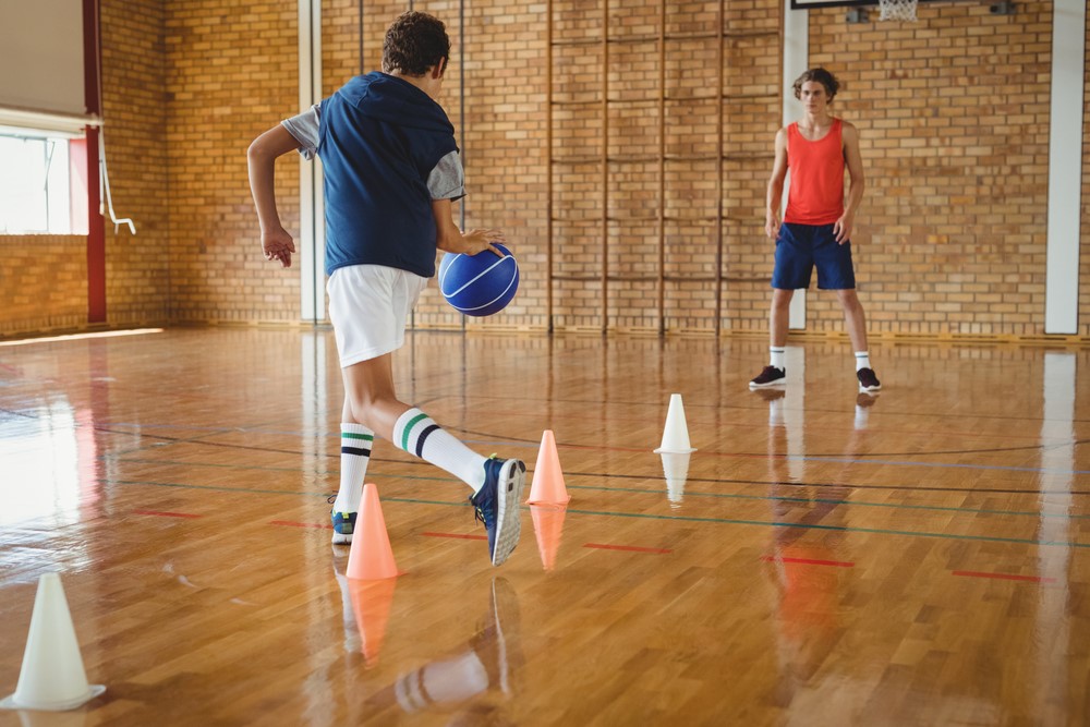 Two boys doing basketball conditioning in a gym