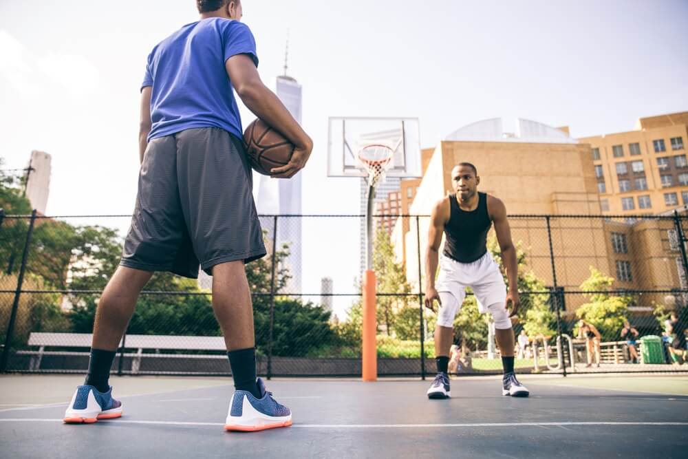 Two young males playing basketball on an outdoor court