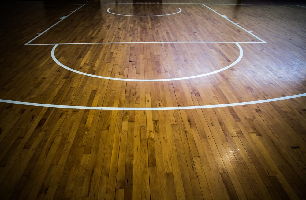 White lines on a wooden basketball court, including the free throw line and top of the key