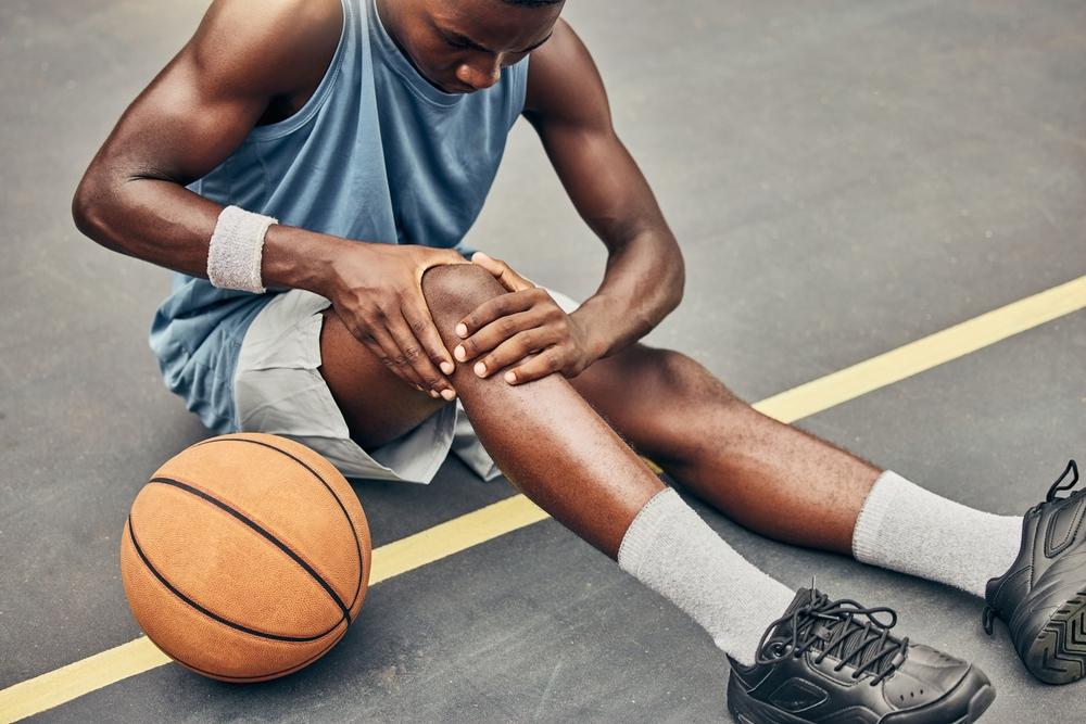 Young man with knee injury on basketball court
